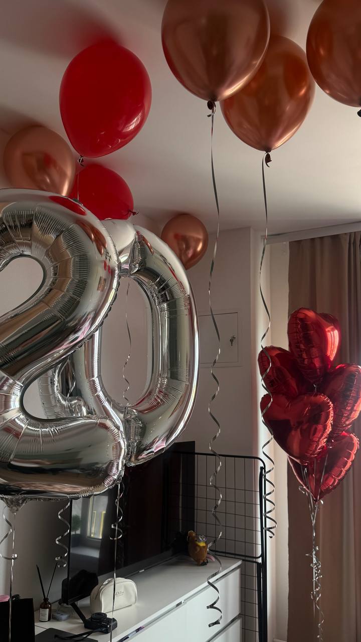 Серебряные цифры «20», красные и медные шары в комнате